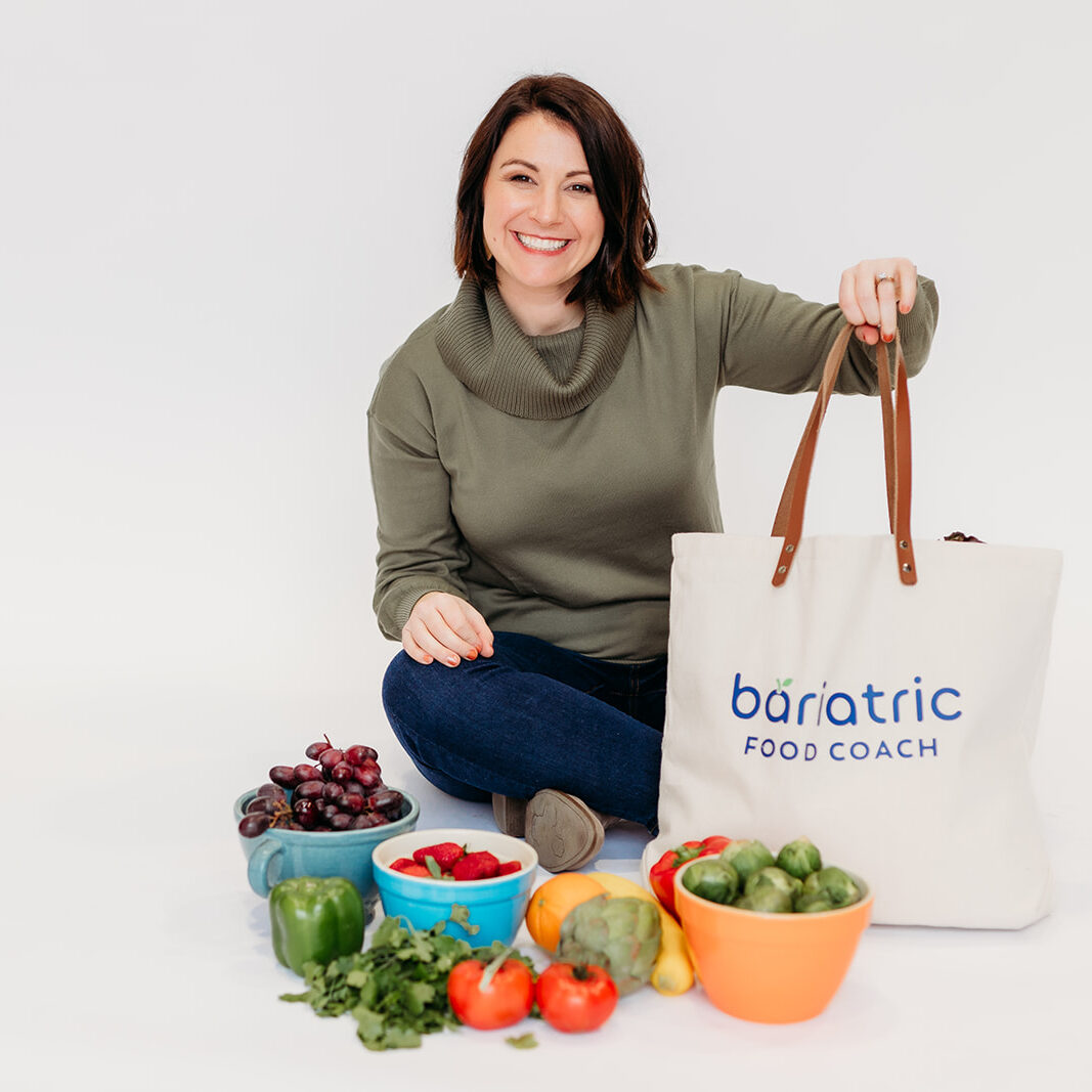 steph holding grocery bag and sitting next to fruit and vegetables.